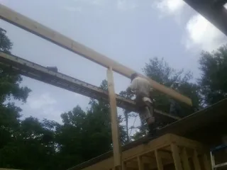 Carpenter setting a ridge beam over a new addition frame — Ice Dam Removal by Roofing Brothers in West Leyden
