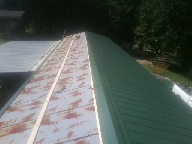 Old rusted panels beside newly installed green metal roofing — Wind Damage Roof Repair by Roofing Brothers in West Leyden