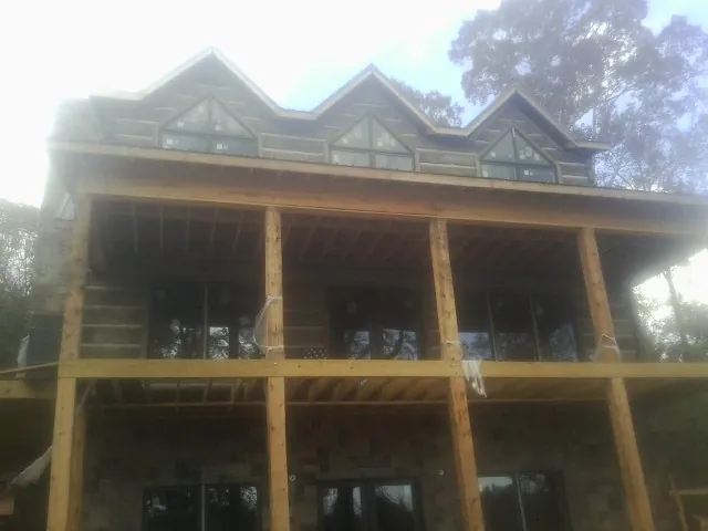 Dormers and porch framing on a large log home under construction — Roof Coating work by our crew in West Leyden
