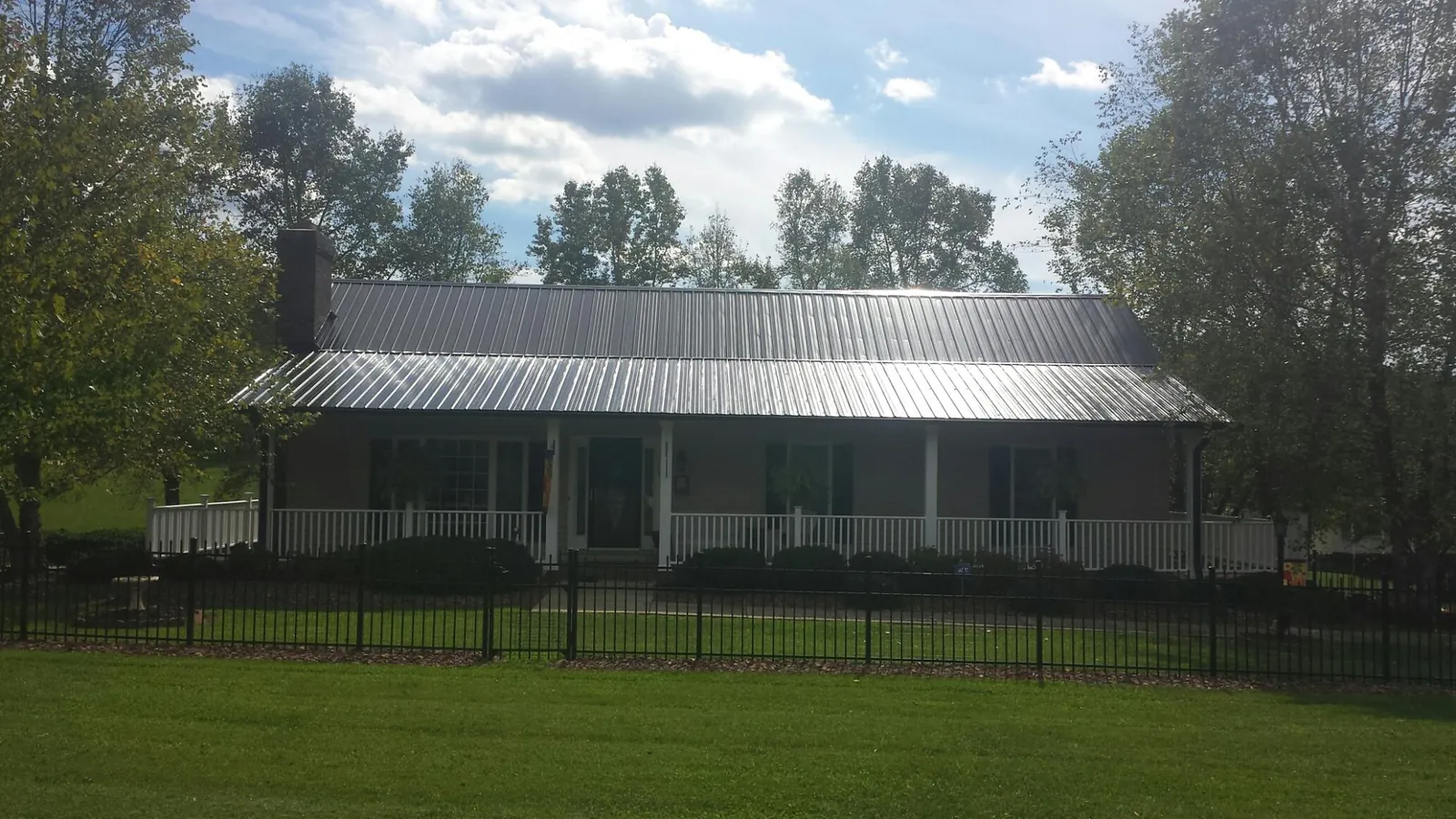 Gray metal roof on a brick ranch with a full width front porch — Gutter Guard Installation work by our crew in West Leyden