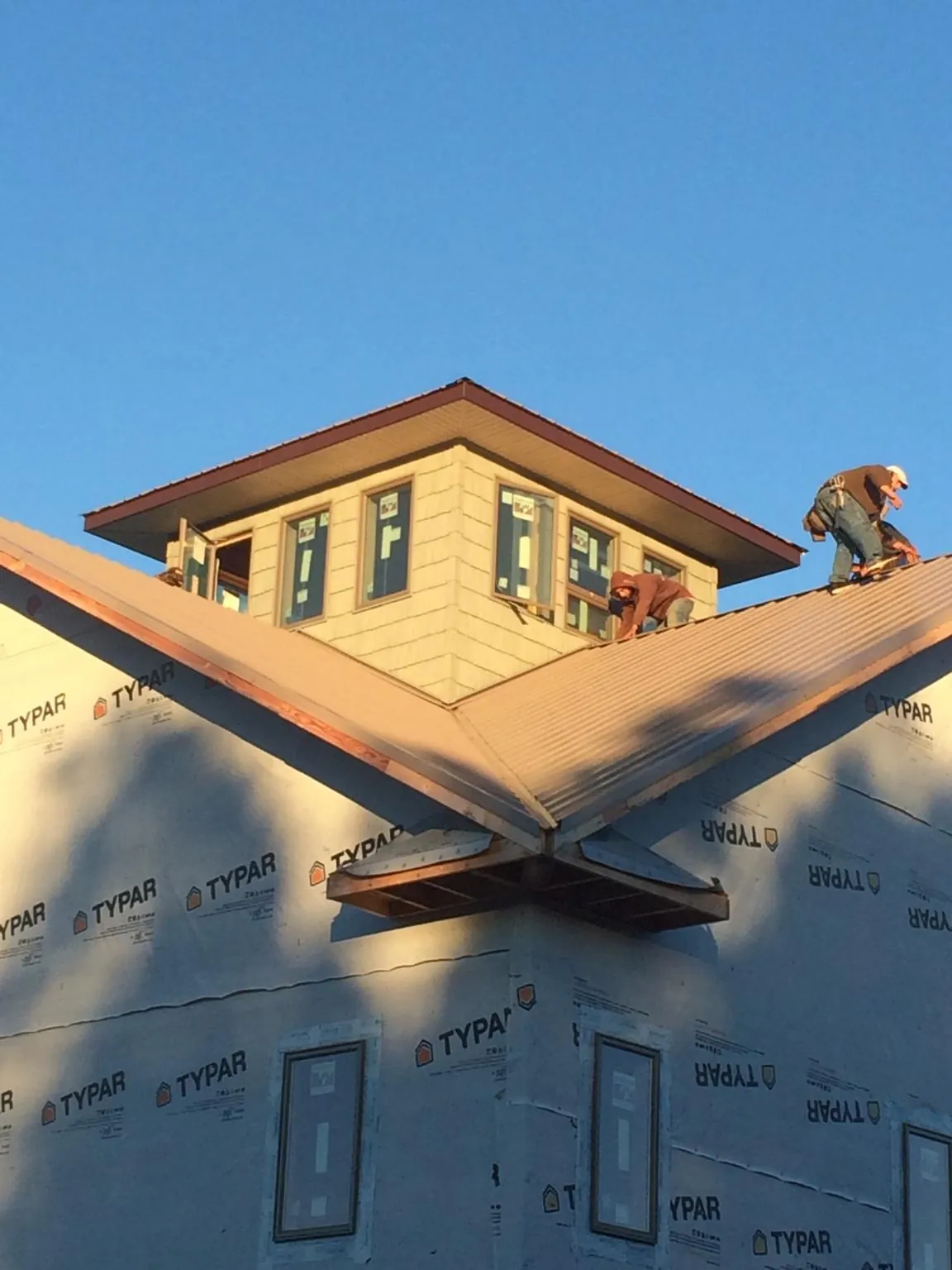 Roofers working around a rooftop cupola on a new metal roof at sunset — Roof Waterproofing in West Leyden by Roofing Brothers